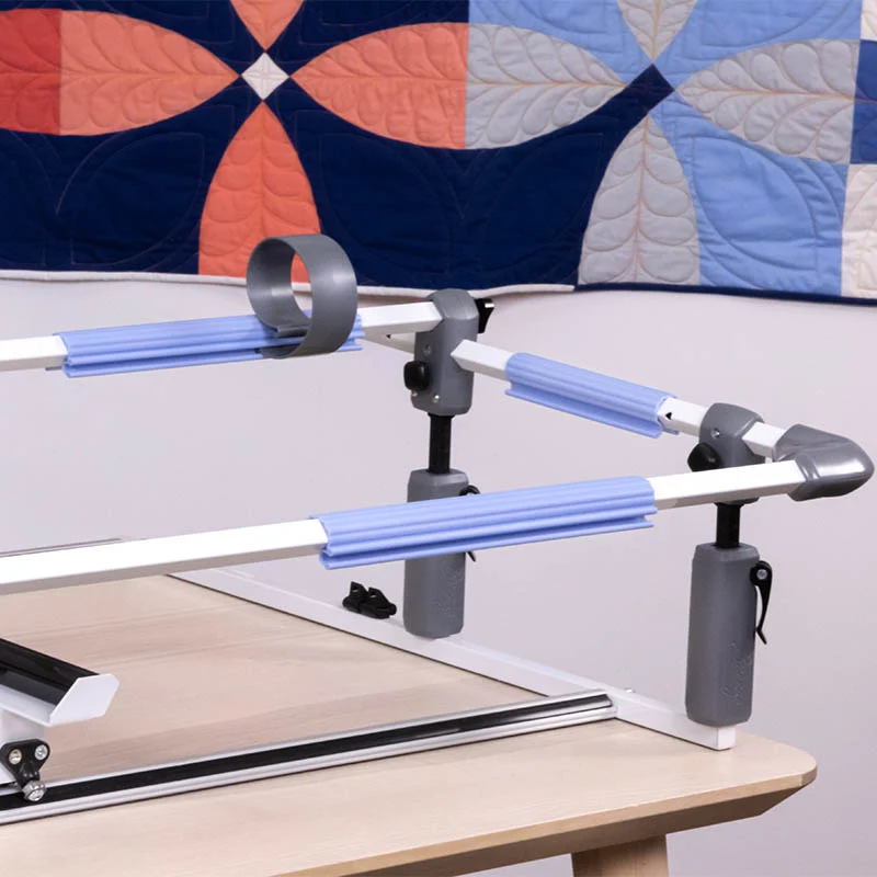 Cadre de quilting Cutie Breeze GRACE en gros plan sur l’un de ses coins, illustrant ses pinces ajustables et ses barres de support bleues pour stabiliser le tissu.