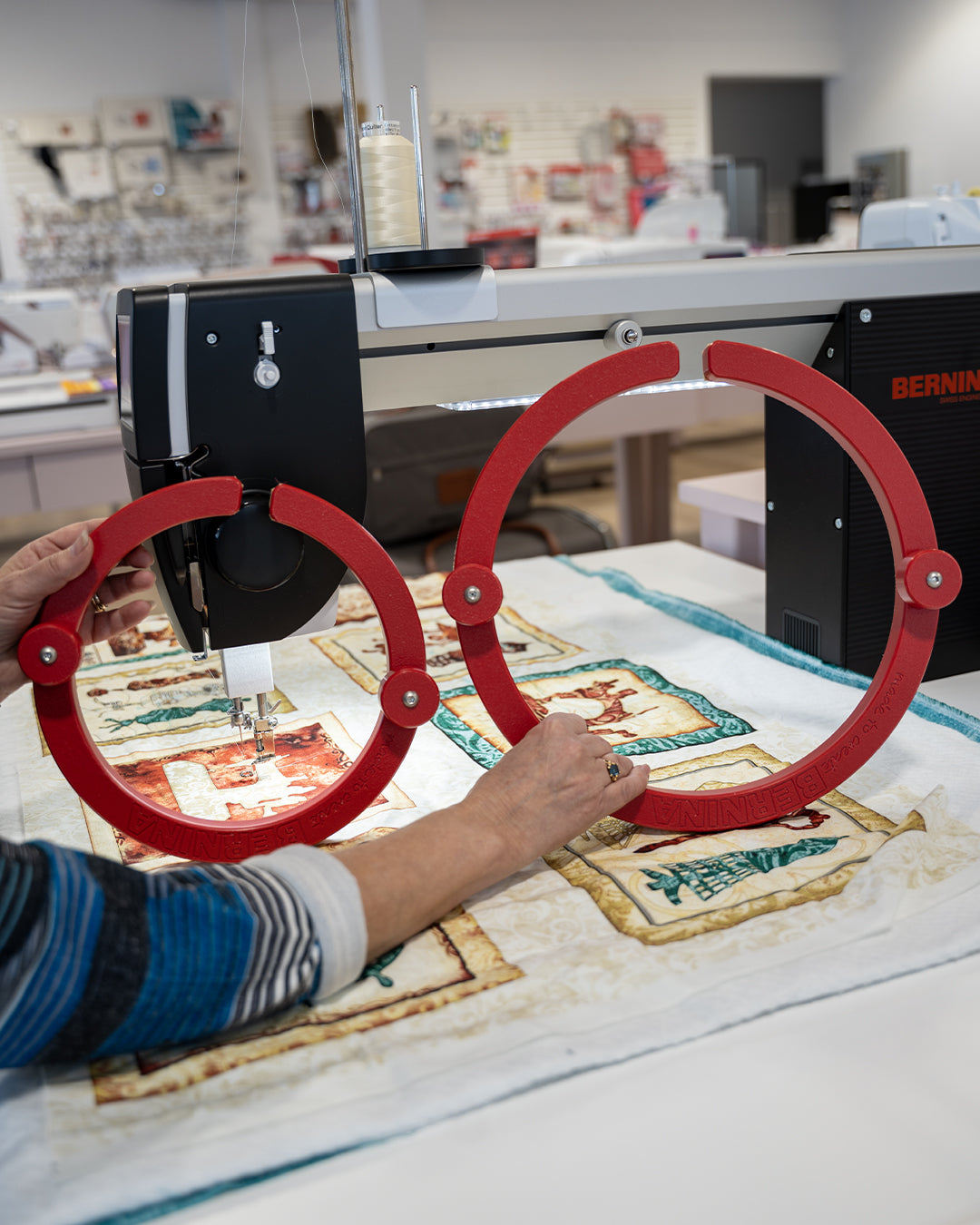 Deux anneaux de préhension Bernina rouges positionnés sur un quilt sous une machine longarm, permettant un meilleur contrôle du tissu.