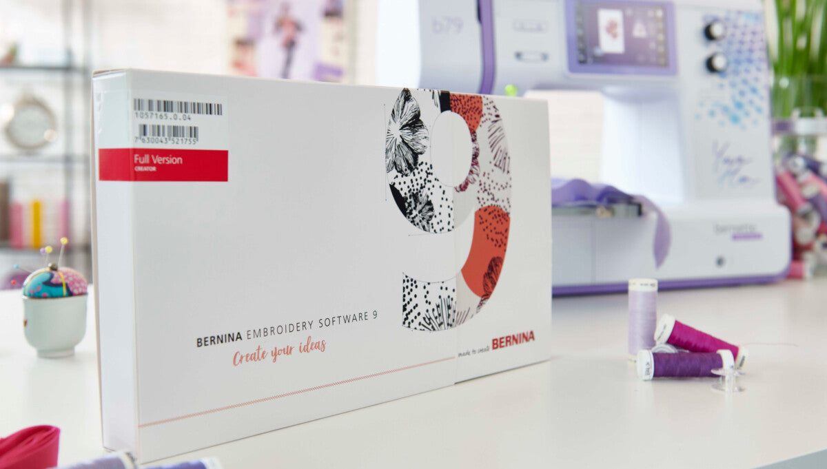 Logiciel de broderie Bernina 9 pour Bernette 79 Yaya Han Edition – Boîte du logiciel de broderie Bernina devant la machine, accompagnée de fils et d’accessoires de couture.