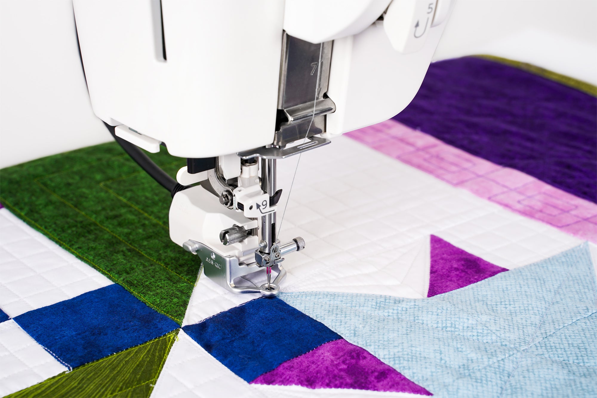 Machine Janome M8 en action sur un projet de courtepointe colorée.