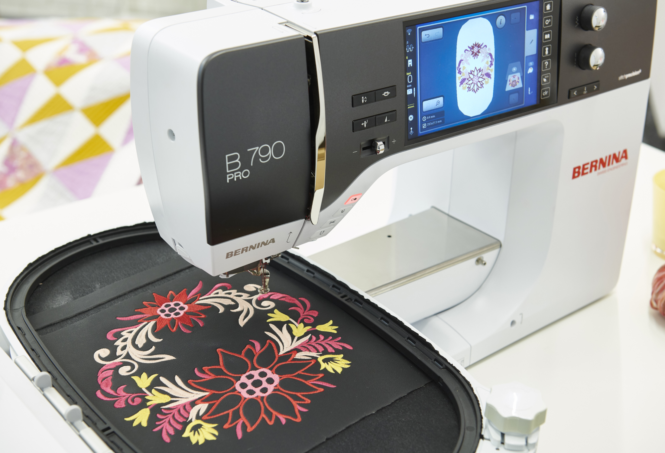 Machine à coudre Bernina B 790 PRO en action – Machine réalisant une broderie florale détaillée sur un tissu noir, illustrant la finesse et la précision de son module de broderie.