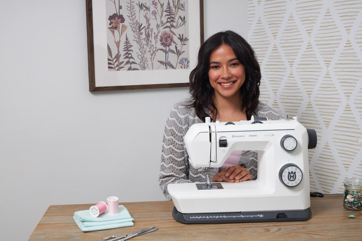 Machine à coudre Husqvarna Viking Onyx 25 – Présentation avec couturière
Femme souriante assise devant la machine à coudre Husqvarna Viking Onyx 25, entourée de matériel de couture, prête à créer.
