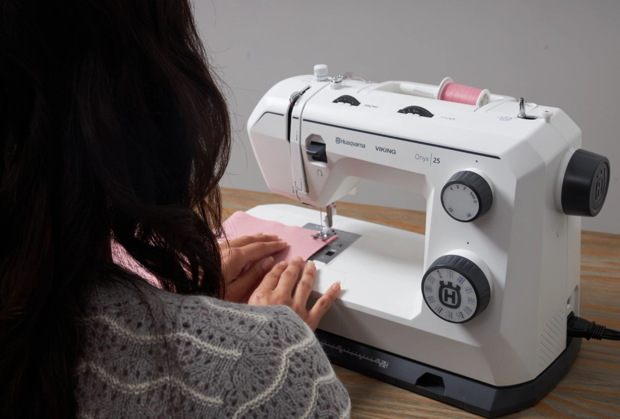 Machine à coudre Husqvarna Viking Onyx 25 en action
Personne en train de coudre du tissu rose avec la machine à coudre Husqvarna Viking Onyx 25, illustrant son utilisation pratique.