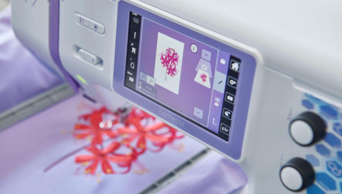 Motif brodé avec la Bernette 79 Yaya Han Edition – Vue rapprochée d’un motif floral rouge brodé sur un tissu violet, affiché également sur l’écran tactile.