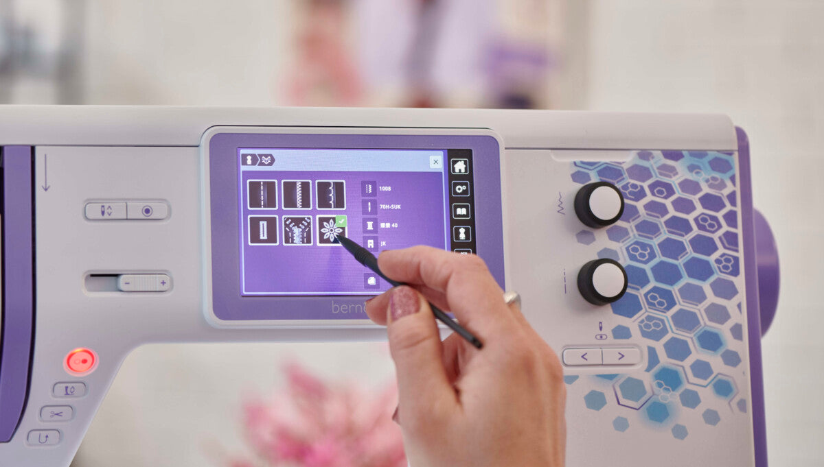 Écran tactile Bernette 79 Yaya Han Edition – Sélection de motifs de broderie via un stylet sur l'écran numérique de la machine.
