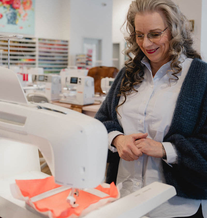 Conseillère d'Excelle Machine à Coudre en train d'utiliser une machine à broder en boutique