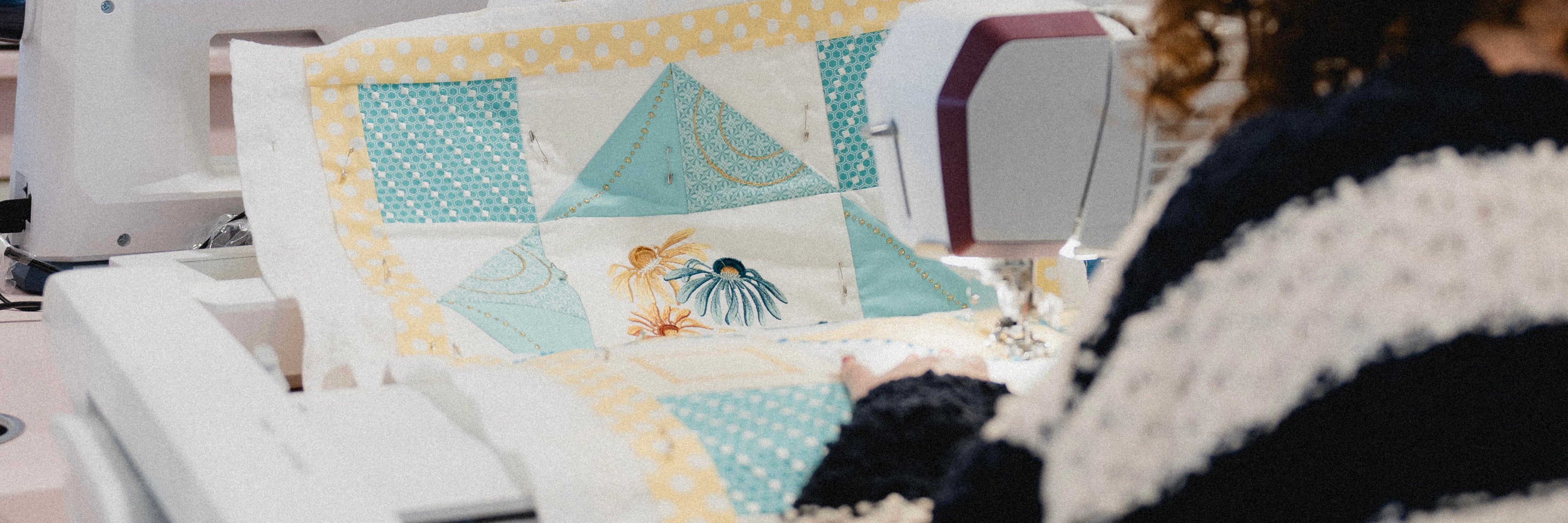 Jeune femme en train de piquer une courtepointe dans les teintes turquoise, blanc et jaune