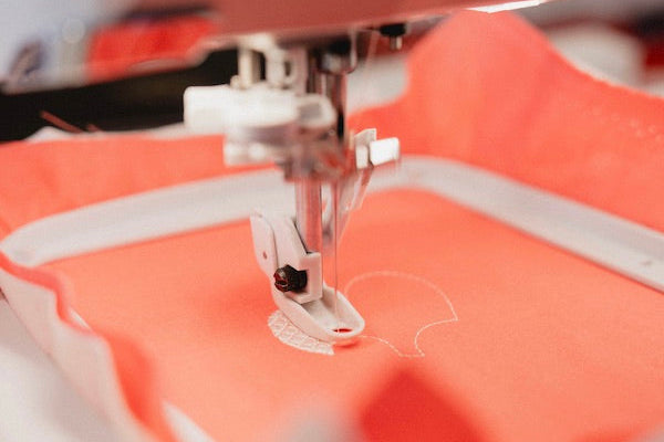 Gros plan sur une broderie réalisée sur un tissu corail, à l'aide d'une machine à broder