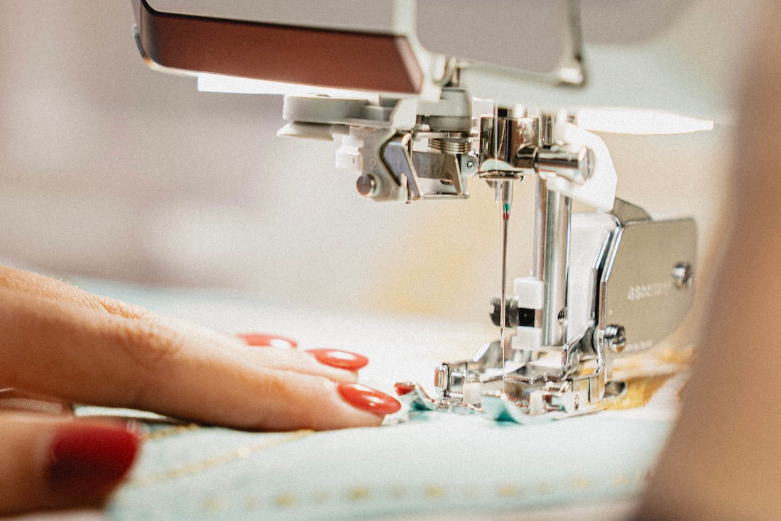 Gros plan sur les mains d'une couturière qui utilise une machine à coudre