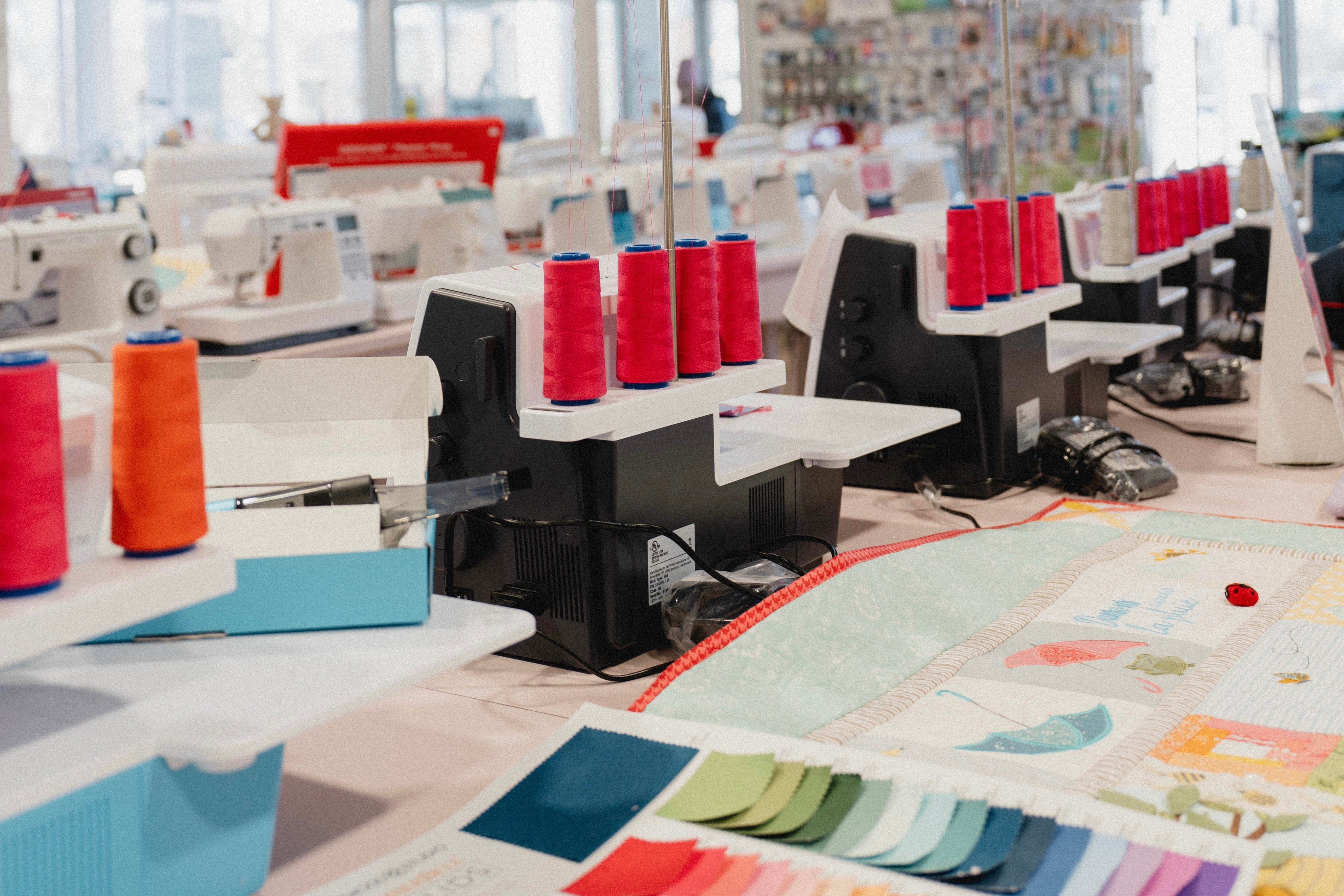 Intérieur de la boutique Excelle Machine à Coudre à Laval avec machines à coudre, fils de couleur rouge et accessoires de couture et courtepointe