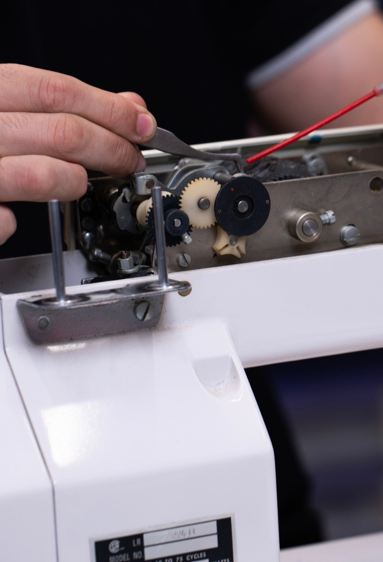 Une technicienne utilise des outils pour réparer les engrenages d'une machine à coudre