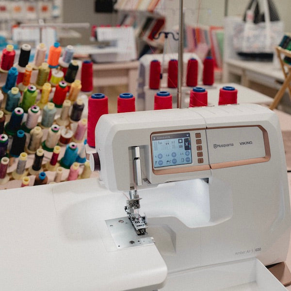 Surjeteuse Husqvarna Viking avec, en arrière-plan, des bobines de fils