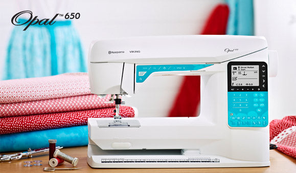 Machine à coudre Husqvarna Viking OPAL™ 650 dans un atelier de couture – Machine en situation, entourée de tissus et d’accessoires de couture, idéale pour la confection de vêtements et de projets créatifs.