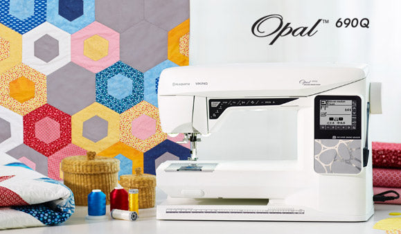 Machine à coudre Husqvarna Viking OPAL™ 690Q en atelier de quilting – Machine en situation avec des tissus et accessoires de couture, idéale pour la confection de quilts et de projets créatifs avancés.