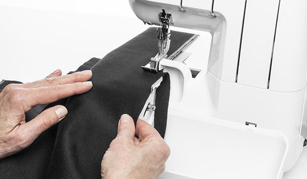 Surjeteuse Husqvarna Viking AMBER™ S | 100 – En action
Gros plan sur une personne utilisant la surjeteuse Husqvarna Viking AMBER™ S | 100 pour couper et surjeter un tissu noir avec précision.