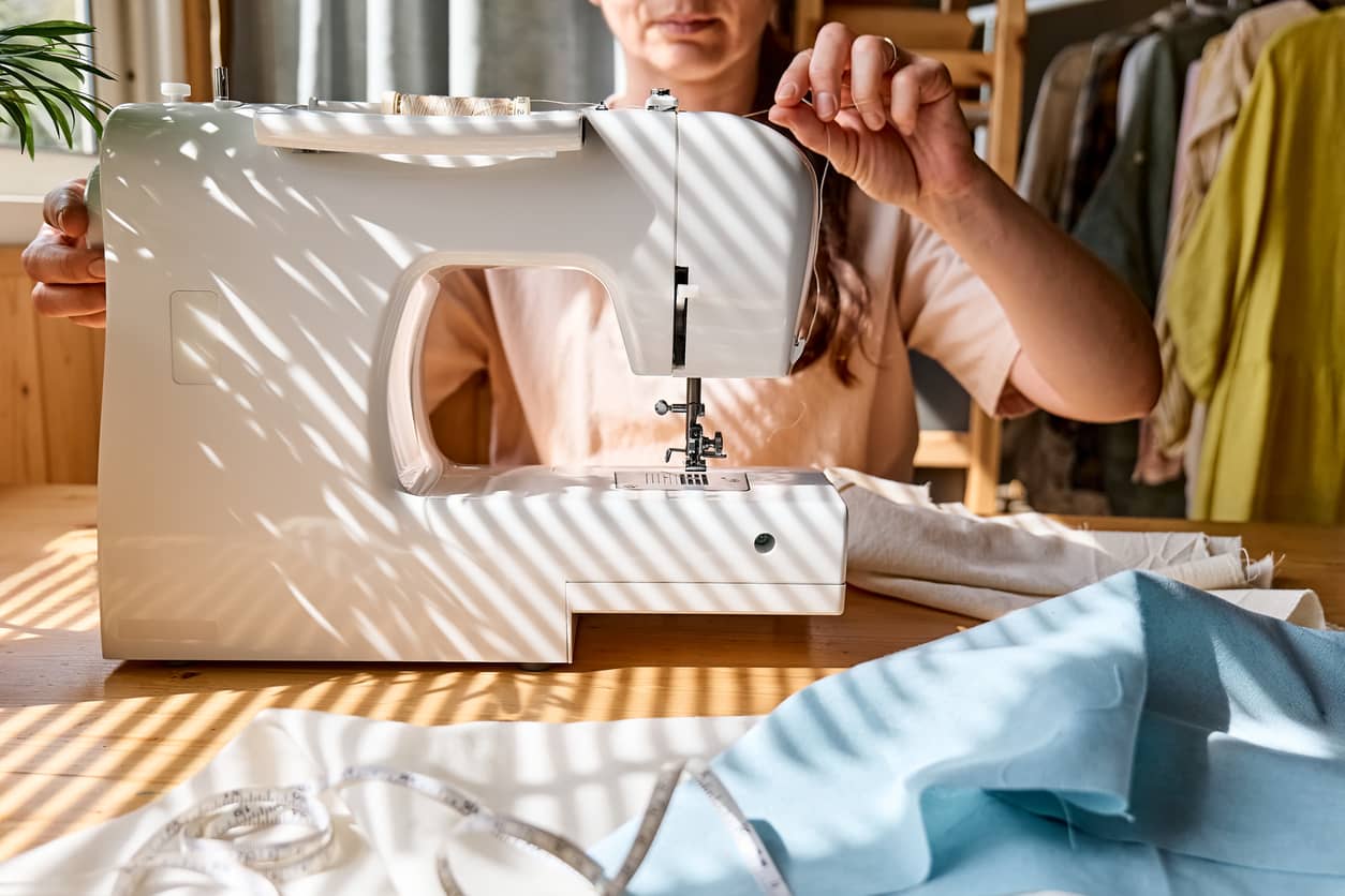 Femme qui ajuste le fil de sa machine à coudre.