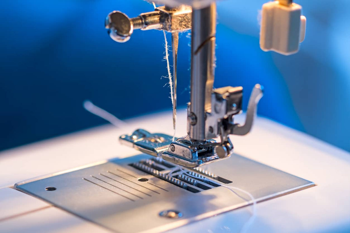 Gros plan sur un fil effiloché près de l’aiguille d’une machine à coudre