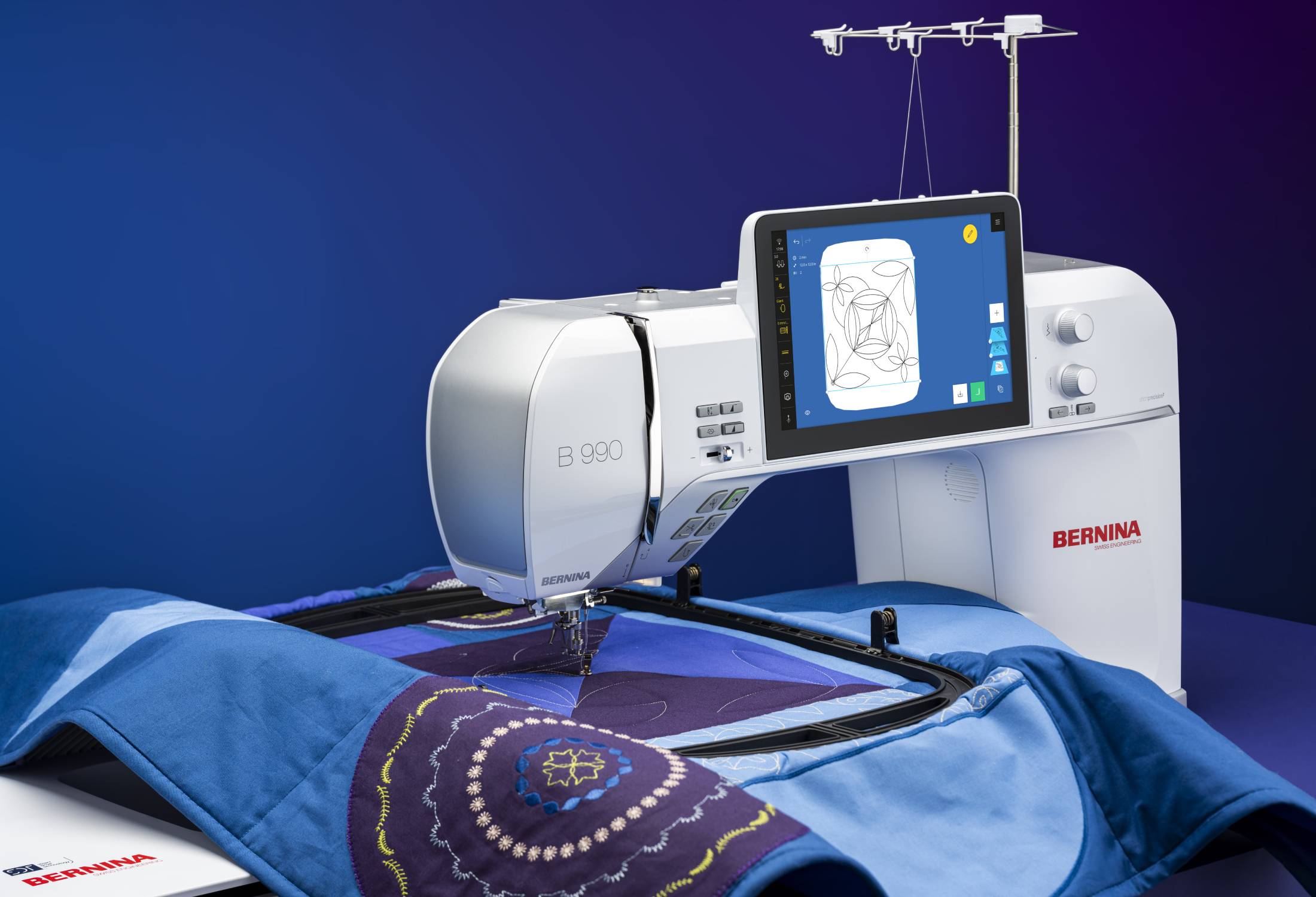 Bernina 990 machine à coudre en action – Machine brodant un motif géométrique sur un tissu bleu et violet, avec un grand cadre de broderie.