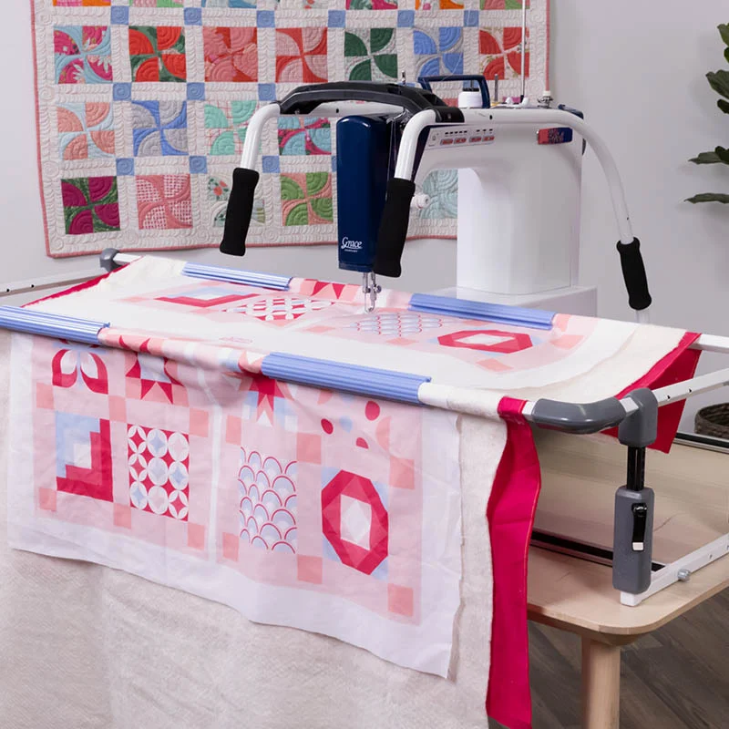 Cadre de quilting Cutie Breeze GRACE avec machine à quilter installée, maintenant un quilt rose et blanc en place pour un quilting précis et fluide.