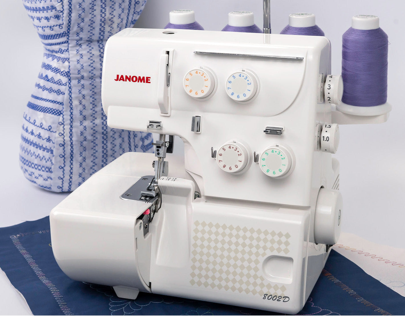 Machine à coudre Surjeteuse Janome 8002D en action – La surjeteuse Janome 8002D utilisée sur un tissu bleu, démontrant sa capacité à réaliser des finitions soignées et résistantes.