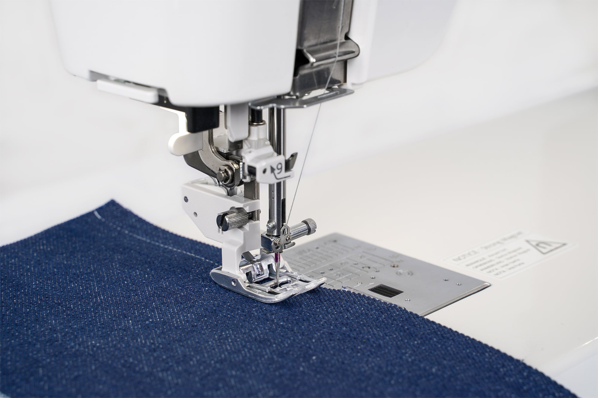 Pied de couture de la Janome M8 cousant du tissu en denim.