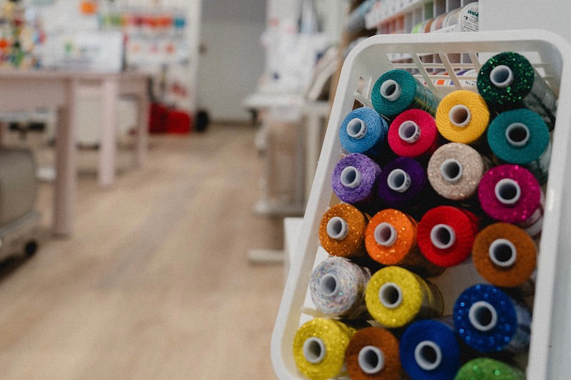Bobines de fils colorés en avant-plan dans un magasin de couture