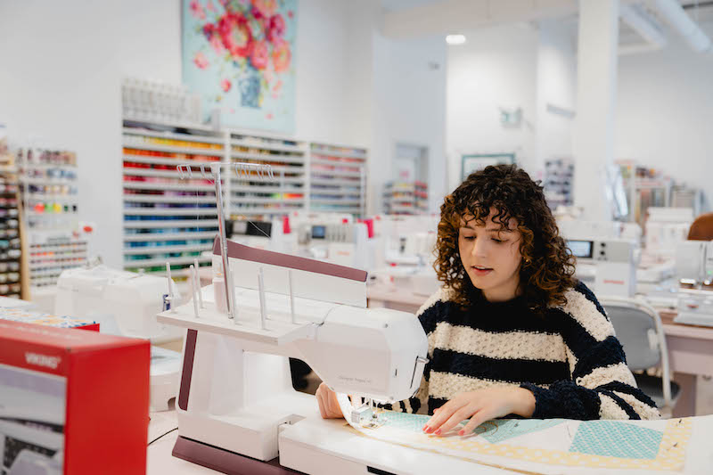Jeune femme réalisant une courtepointe chez Excelle Machine à Coudre