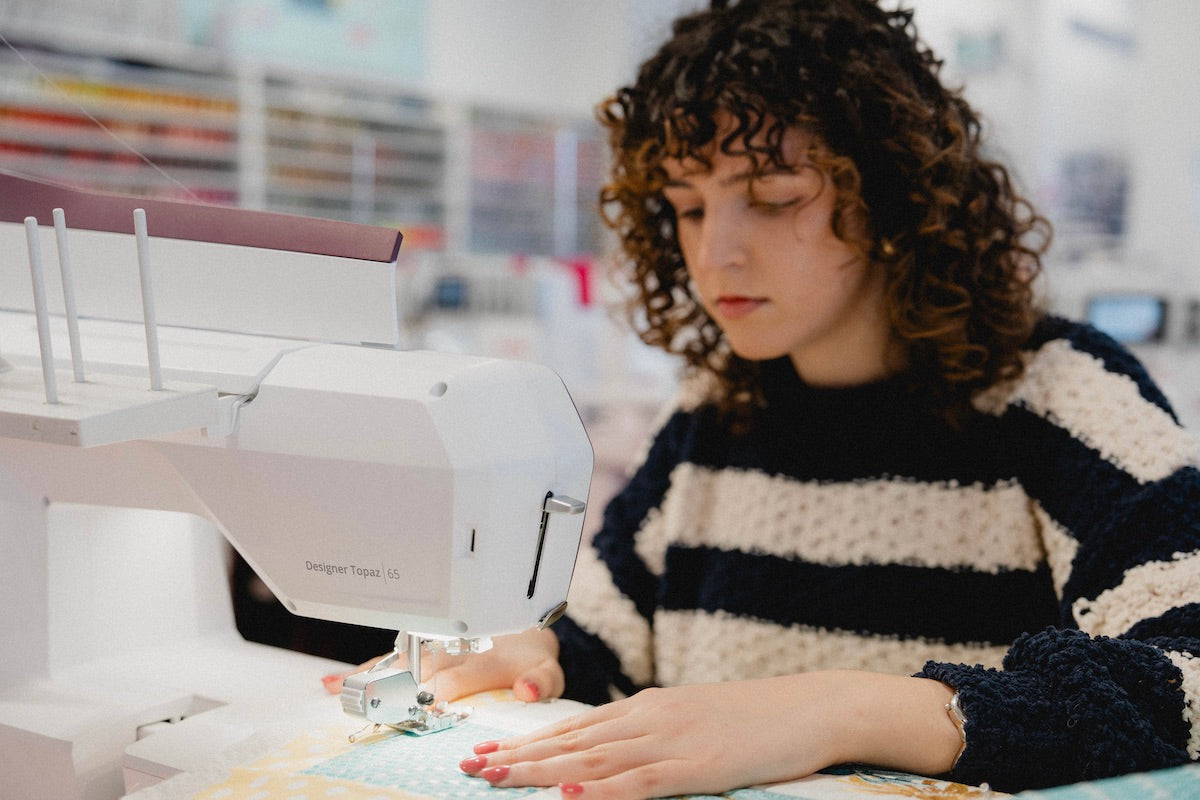Jeune femme concentrée sur son projet de couture  à la machine