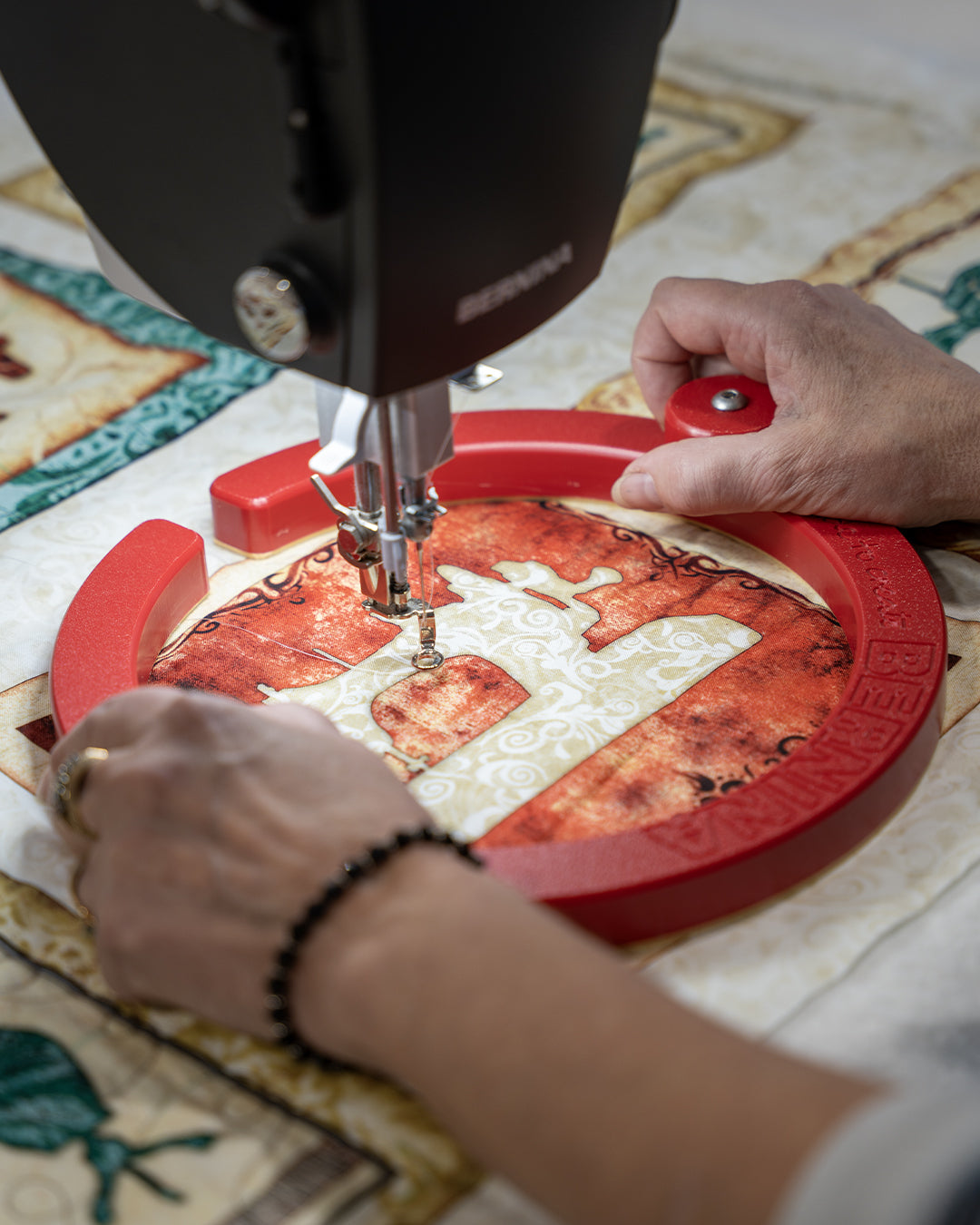 Gros plan sur les mains d'une couturière utilisant un anneau de préhension Bernina pour guider le tissu sous la machine à coudre.