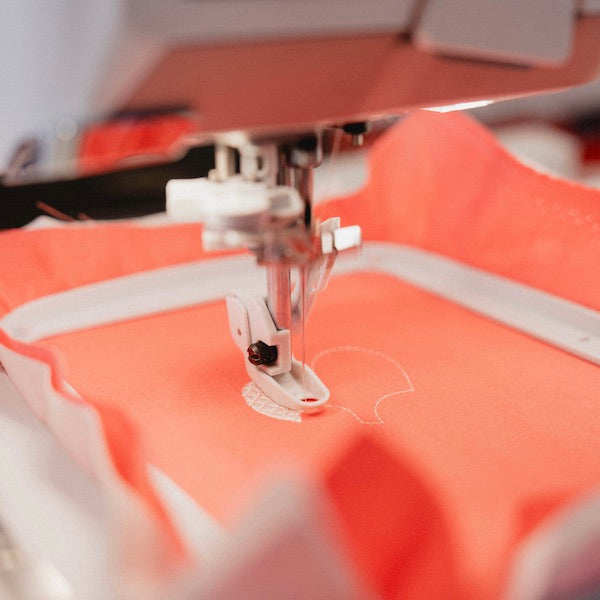 Gros plan sur une broderie réalisée sur un tissu corail, à l'aide d'une machine à broder