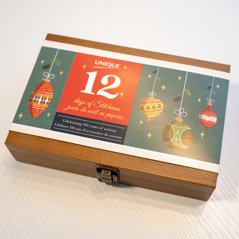 Coffret fermé '12 jours de Noël en piqûres' avec des motifs festifs et un design en bois élégant, prêt pour les surprises de couture.