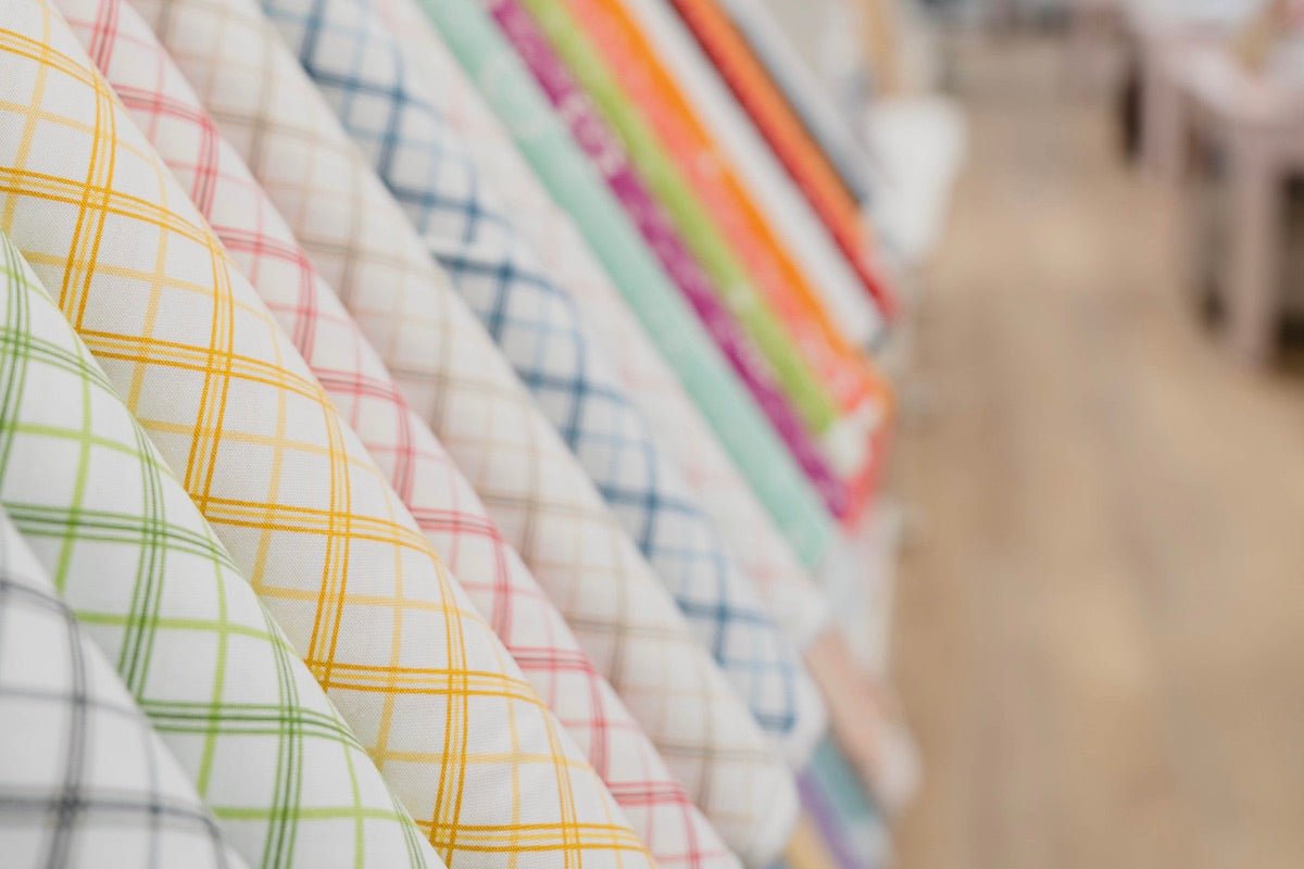 Tissus lignés colorés blanc et vert, blanc et jaune, etc. présentés en boutique chez Excelle Machine à Coudre à Laval