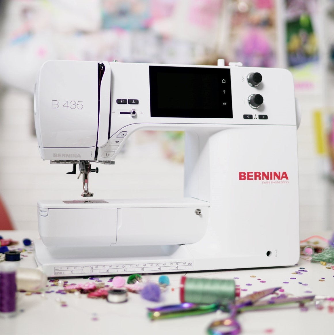 Machine à coudre Bernina 435 dans un atelier créatif, entourée de fournitures de couture et de décoration.