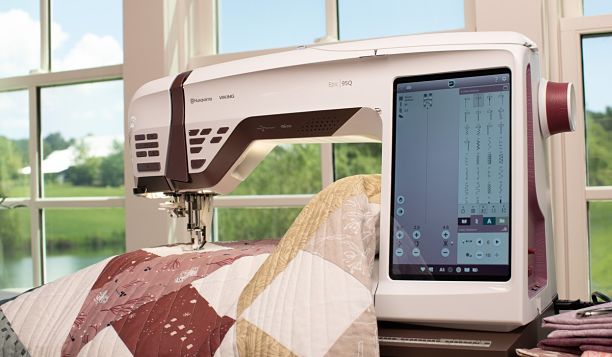 Machine à coudre HUSQVARNA® VIKING® EPIC™ 95Q en action – Machine en cours d'utilisation pour la couture d’un quilt, avec son grand écran tactile affichant des réglages avancés.