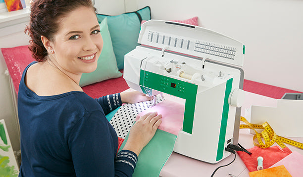 Machine à coudre Husqvarna Viking JADE™ 20 – Utilisation en cours
Femme souriante en train de coudre du tissu coloré avec la machine à coudre Husqvarna Viking JADE™ 20, montrant le grand espace de travail et les réglages faciles d’accès.